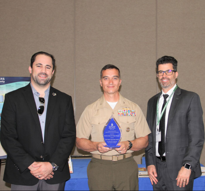 Colonel Charles B. Dockery holds the award alongside two other men.