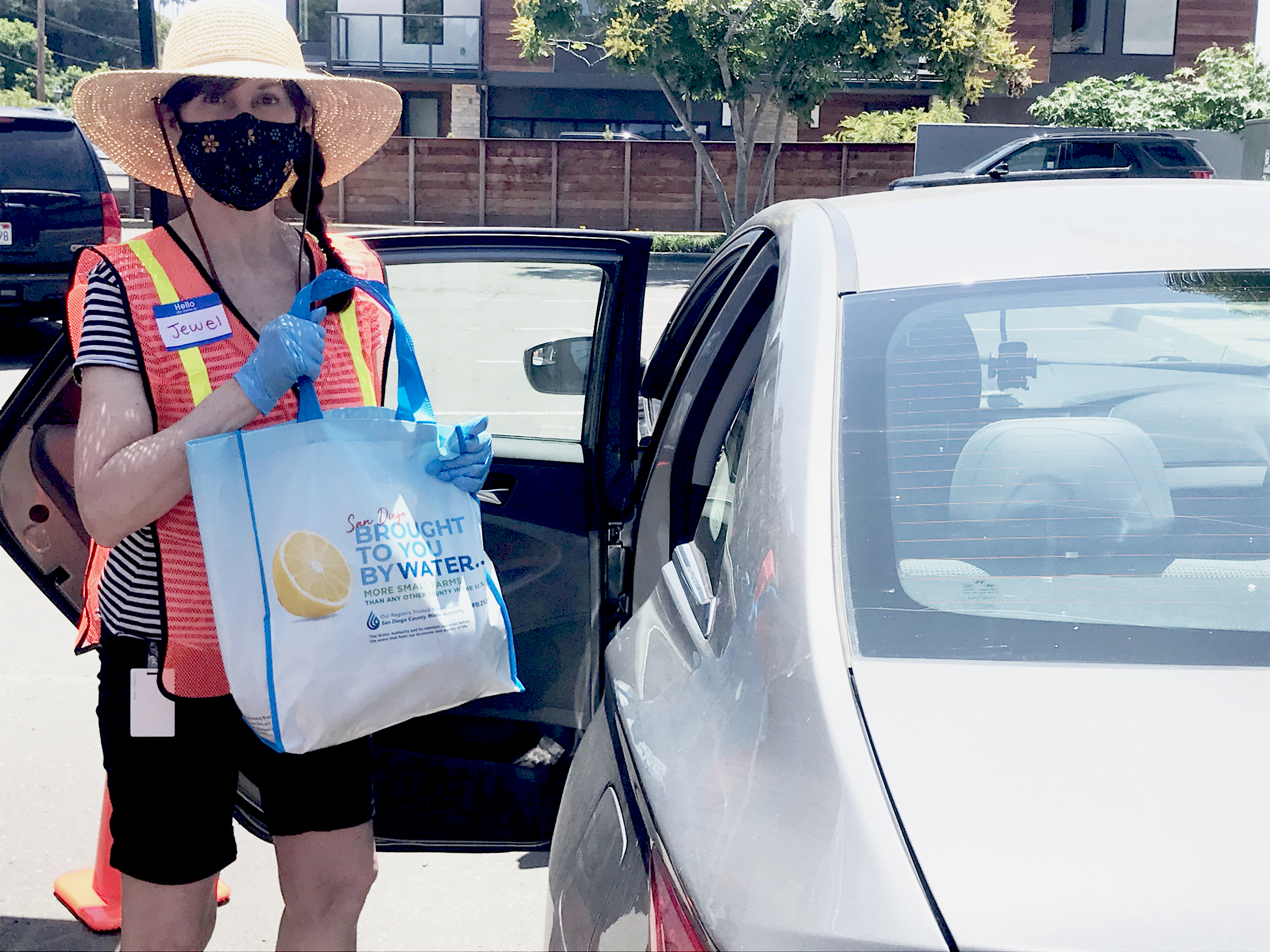 Solana Beach Mayor wearing a face mask holds a bag of food ready to place into a car for a resident.