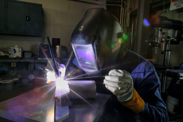 person welding with futuristic looking face shield